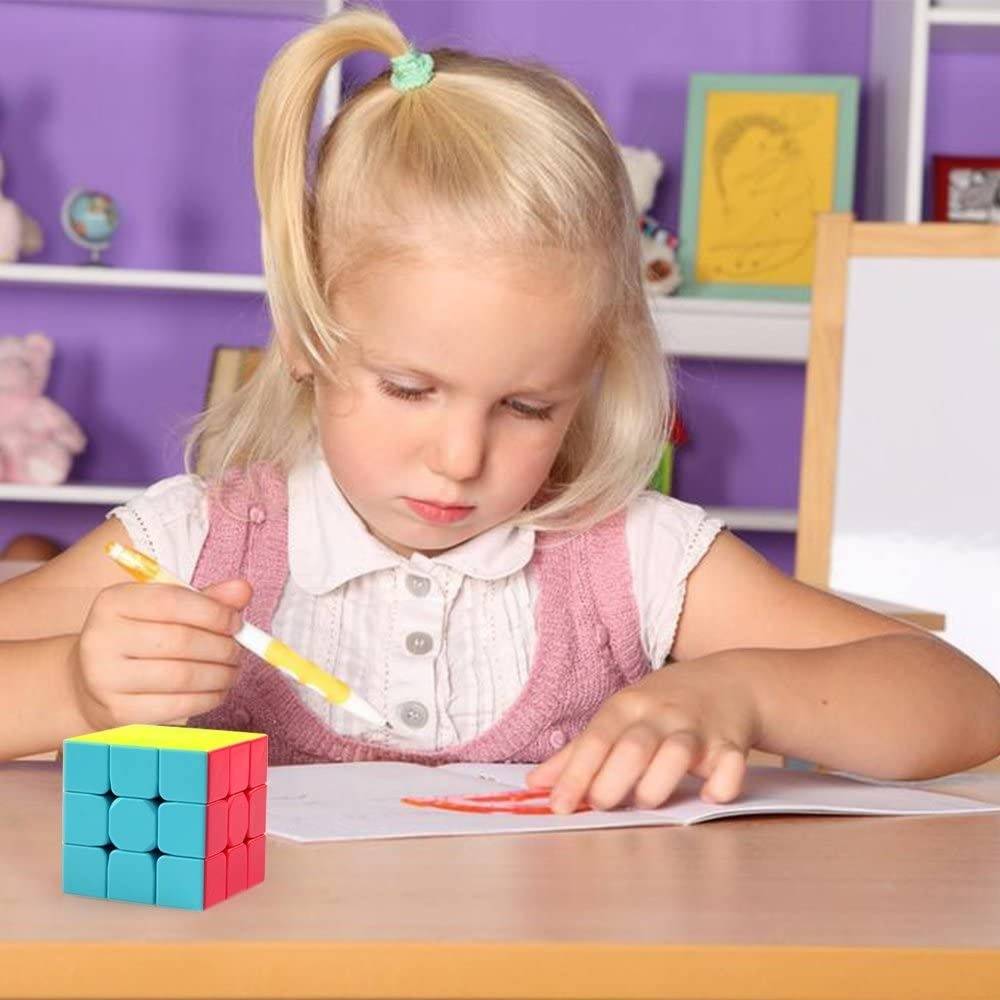 3 By 3 Rubik Cube 3x3 - shown as a multi-colored cube with yellow, blue, and red faces sitting on a desk next to a young girl drawing in a notebook.