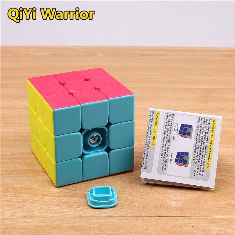 3 By 3 Rubik Cube 3x3 - with pink, yellow, and blue panels, featuring a detached center cap and an instructional paper guide on a wooden surface.