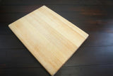300MMX400MMX10MM wood project board - a rectangular, light-colored wooden board placed diagonally on a dark, horizontal-planked wooden surface.