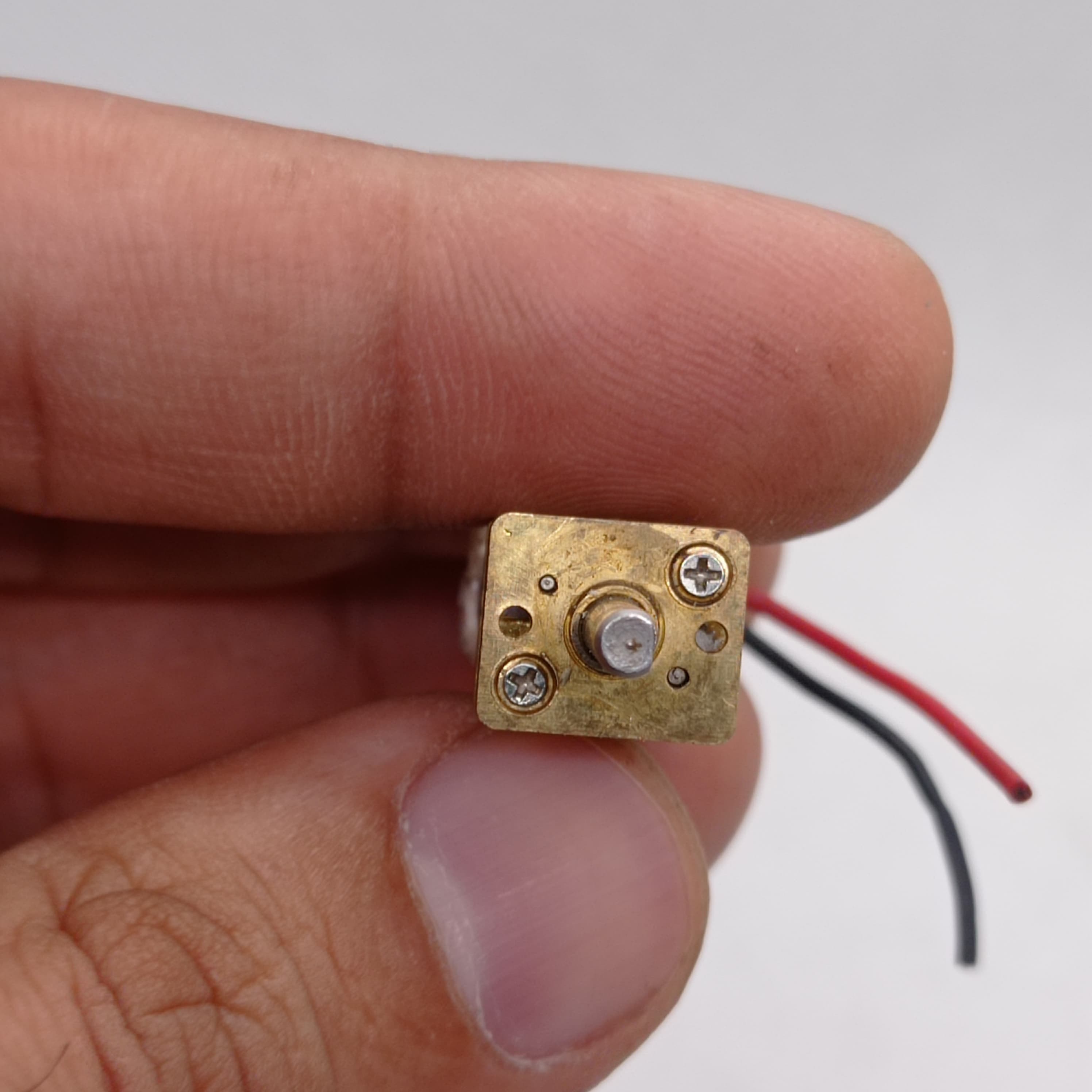 300RPM N20 DC Gear Motor The Perfect Low RPM High Torque Motor For Your Electronics Projects - a close-up view of the brass-colored gearbox face with a central output shaft, two mounting screws, and red and black wires.