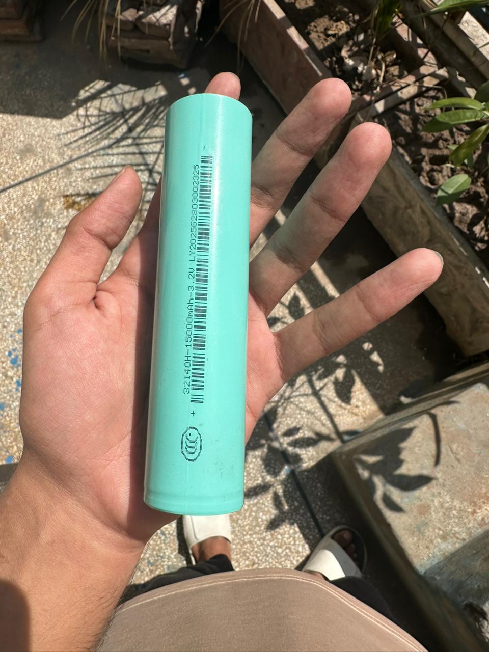 32140 3.2V 15A LiFePO4 Cell - the light blue cylindrical body with printed specifications and a barcode.