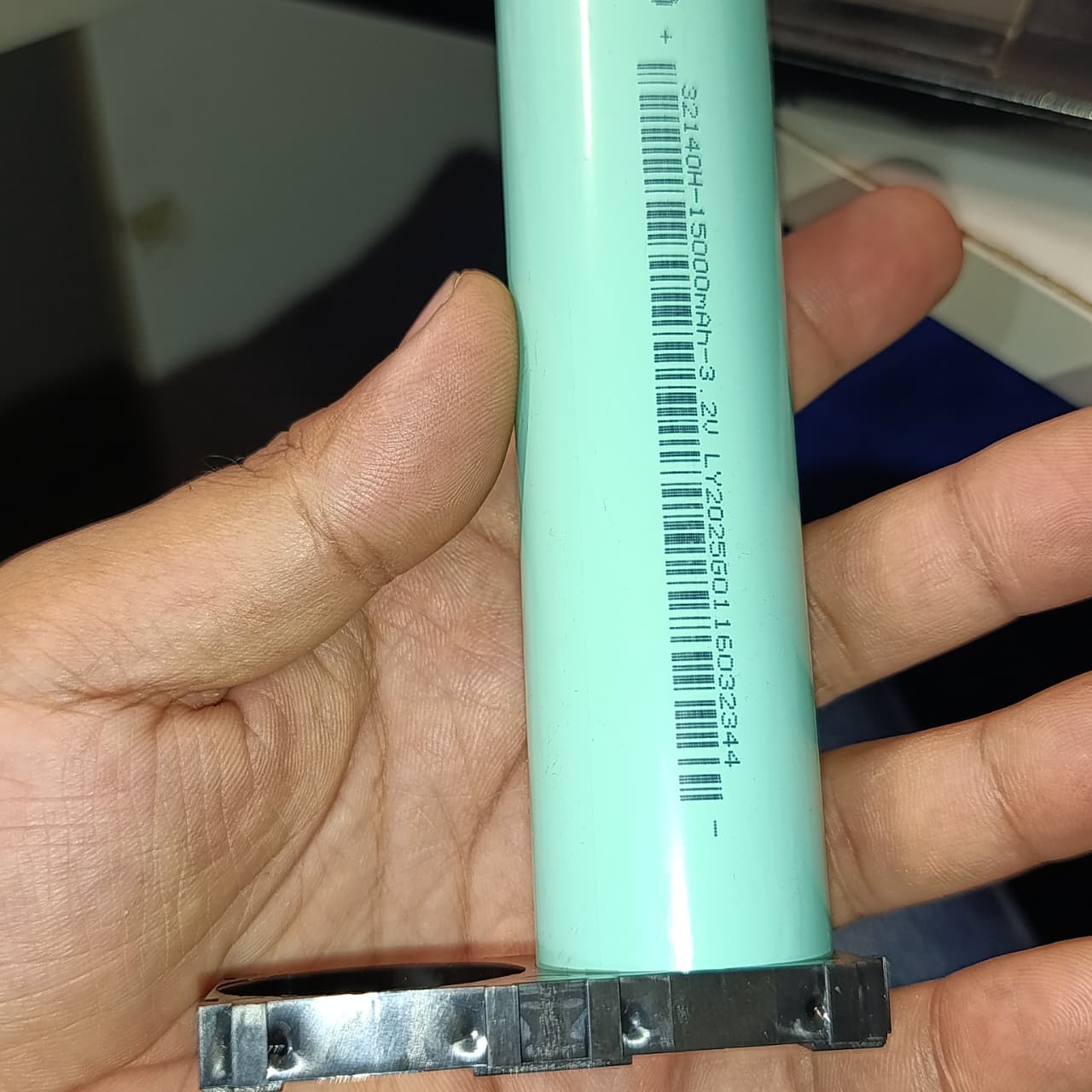 32140 Lithium Cell Holder Bracket - Dual Cell Spacer - a black plastic spacer holding a light green cylindrical battery with printed text and a barcode.