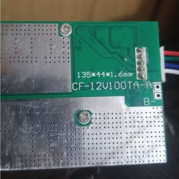 32650 Cell 4s BMS 100A 12V Battery Charging Module Cf 12V100TA a PCB Protection Board - a close-up of a green rectangular circuit board with a silver metal plate and a five-pin connector.