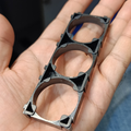 32700 Lithium Cell Holder Bracket - 3P Triple Cell Spacer - a black plastic triple-cell spacer with three circular slots held in a hand.