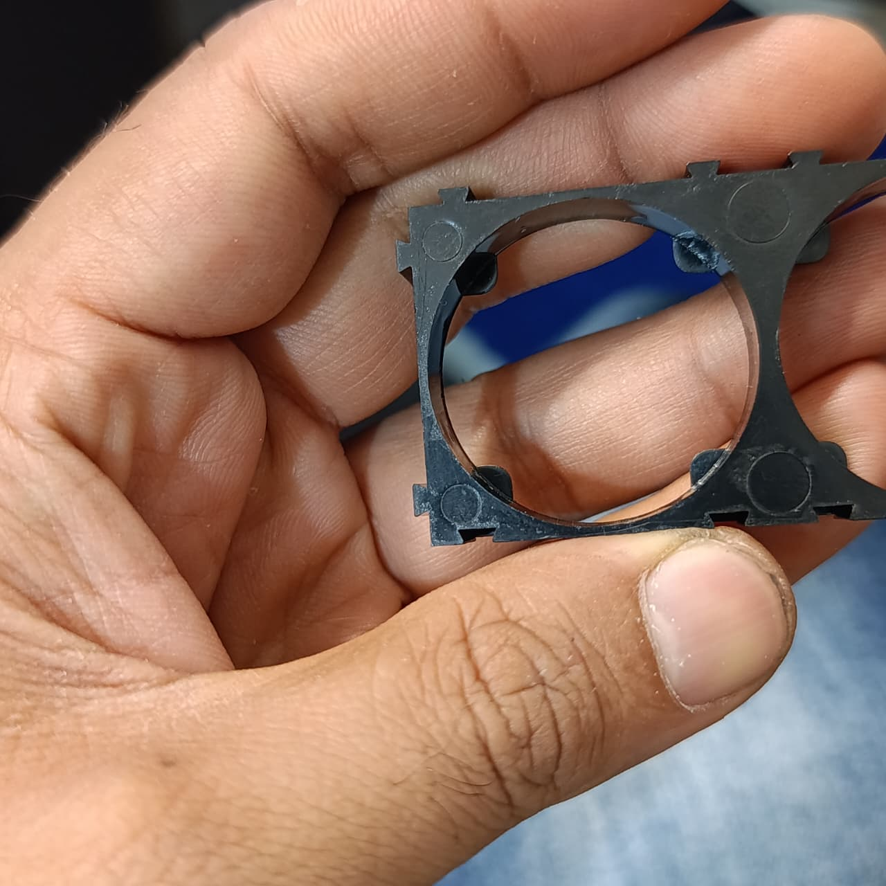 32700 Lithium Cell Holder Bracket - 3P Triple Cell Spacer - shown as a close-up of a single black plastic circular cell housing held in a hand.