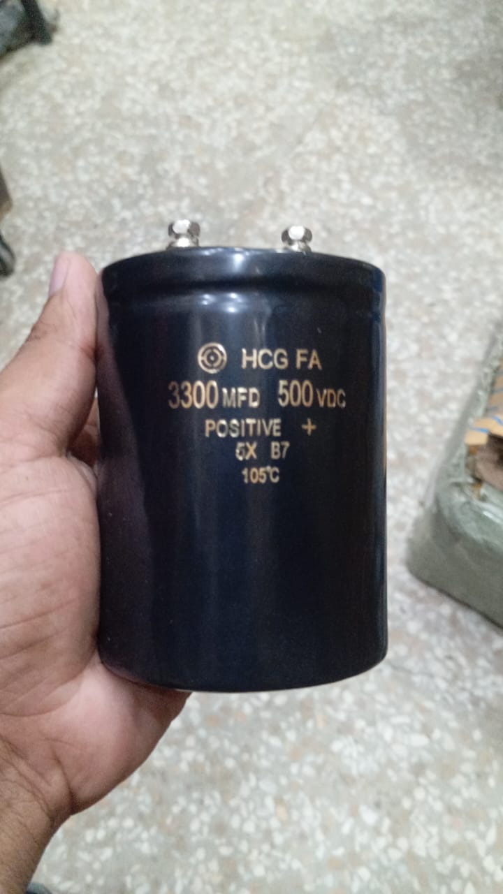 3300µF 500V Electrolytic Capacitor price - a large black cylindrical component held in a hand, featuring two metal terminals on top and printed technical specs.