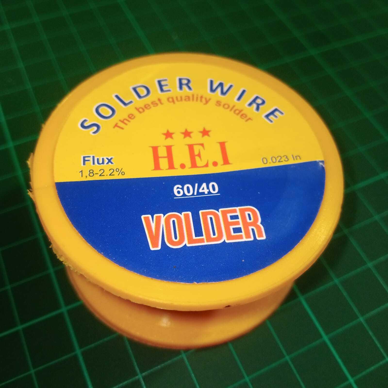 35 Gram Net Weight Solder Wire ( Weight Including Packing Material) - a yellow plastic spool with a round label showing the H.E.I. brand, 60/40 alloy composition, and 0.023 inch wire diameter.