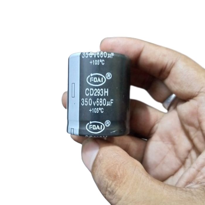 350V 680uF Capacitor - held in a hand, showing a black cylindrical body with the FOAI brand, CD293H model, and 350V 680uF +105°C specifications printed.