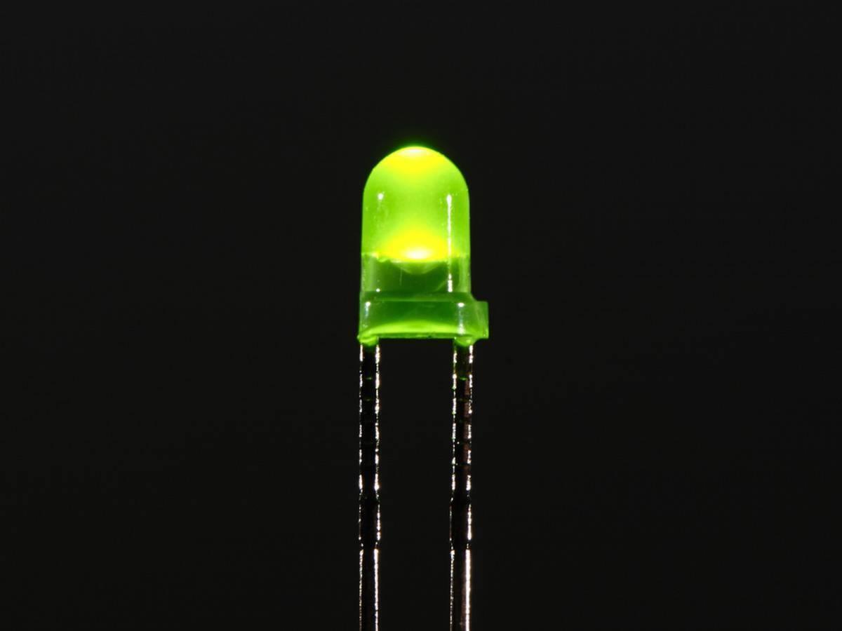 3mm Green LED - a small round green light-emitting diode glowing against a black background with two metal pins extending downward.
