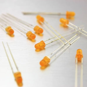 3mm Orange LED - a scattered collection of small, round, orange-coloured light-emitting diodes with two metal leads each on a metallic surface.