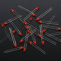 3mm Red LED - a scattered pile of small, round, red-colored light-emitting diodes with two metallic leads each, set against a dark background.