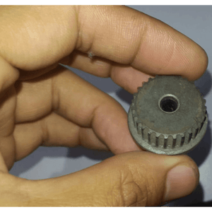 3mm Timing Pulley P28 - a close-up view of a grey, circular, toothed timing pulley with a center hole, held between a person's fingers.