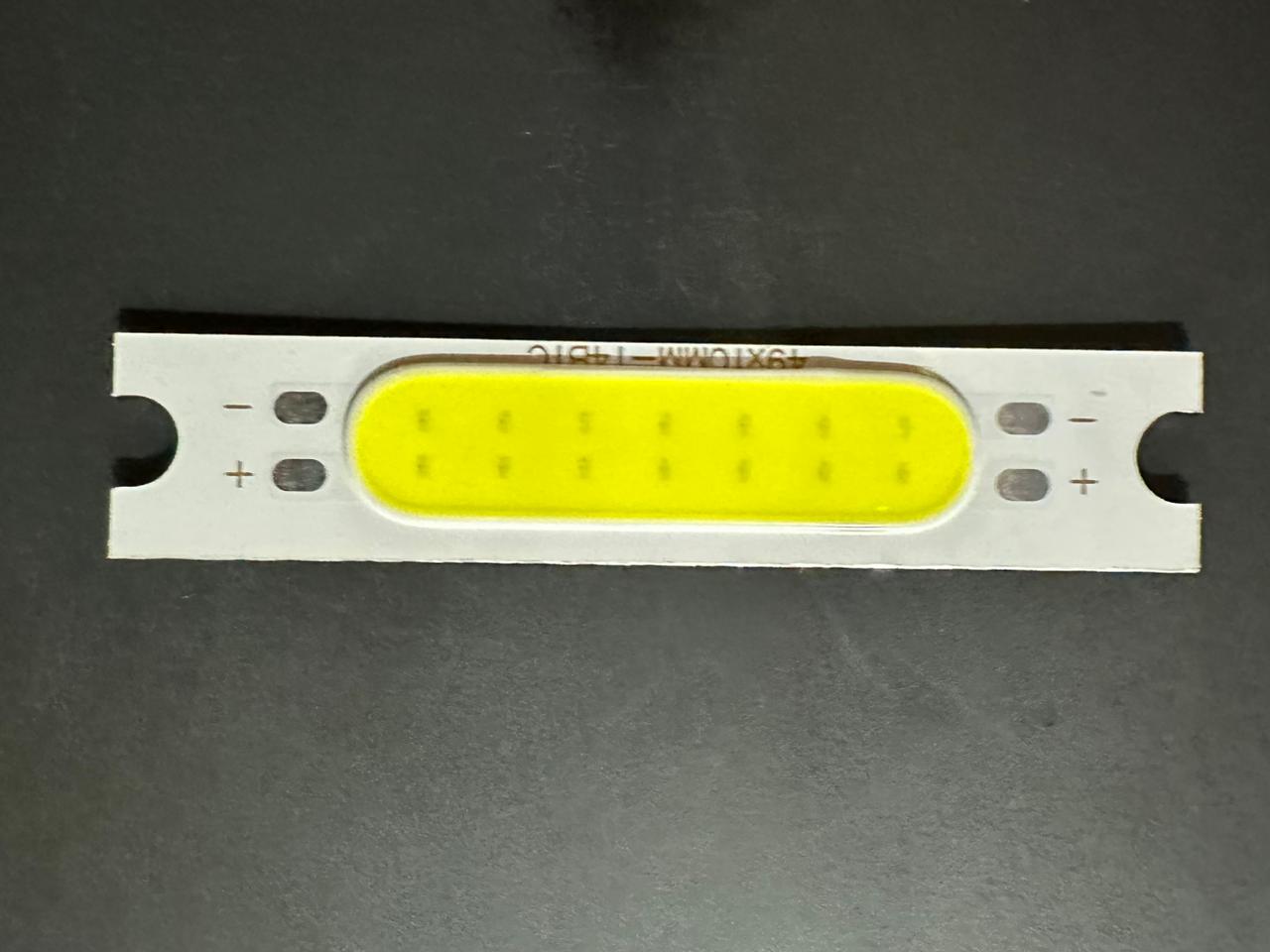 3W 3.7V 1000mA 300LM LED COB Light Module - a rectangular white circuit board with a yellow light-emitting strip and marked positive and negative terminals.