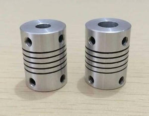 3x6.35mm Flexible Coupling Shaft - two silver cylindrical metal couplings with spiral cuts and four threaded holes each on a light surface.