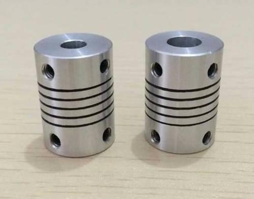 3x6.35mm Flexible Coupling Shaft - two silver cylindrical metal couplings with spiral cuts and four threaded holes each on a light surface.