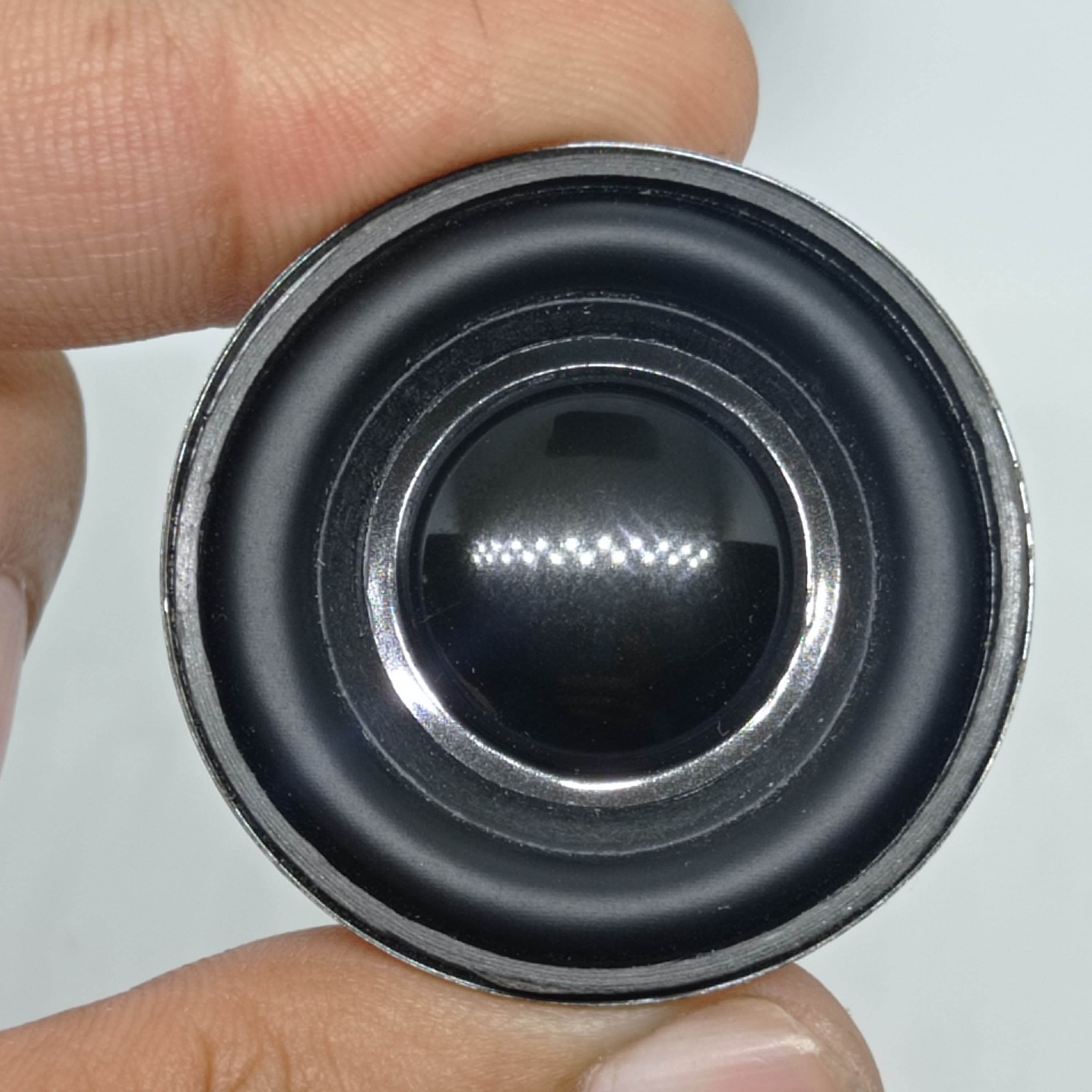 4 Ohm 3 Watt Speaker - a close-up view of a small circular black speaker with a metallic outer rim being held by fingers.