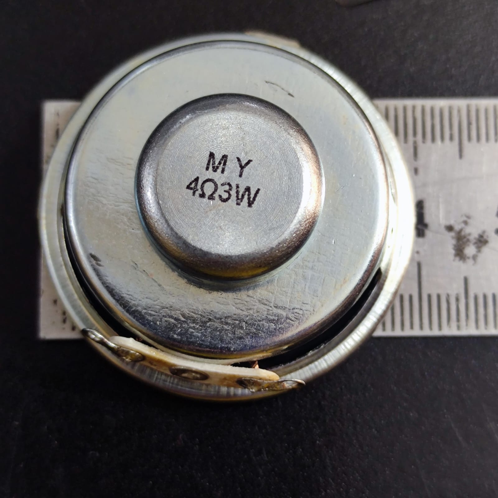 4 Ohm 3 Watt Speaker - a close-up showing the circular metal back of the speaker with "MY 4Ω3W" printed on it, positioned next to a ruler for scale.