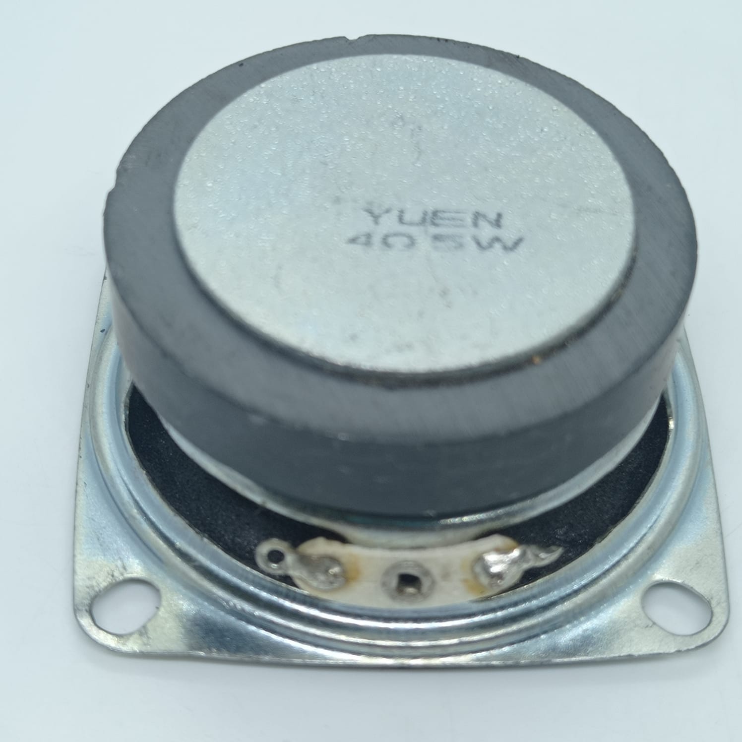 4 Ohm 5 Watt Speaker - the back of the square metal frame with a circular black magnet and two soldered terminal connection points.