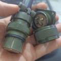 4 Pin Military Connector - High Power Current - shown as a close-up of a green, two-piece circular metal connector held in a hand.