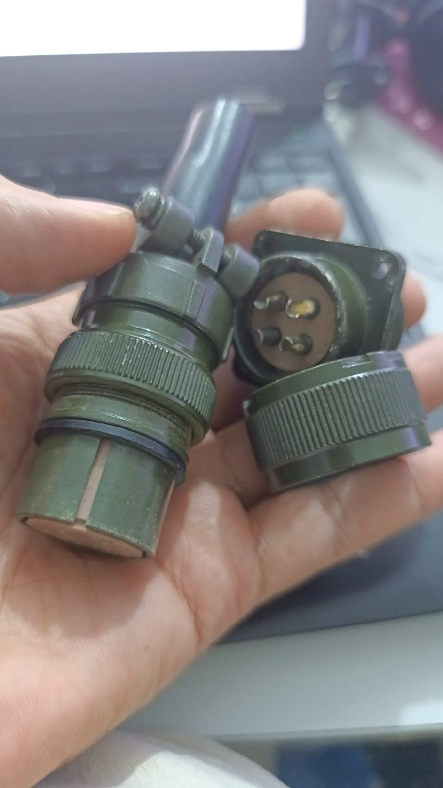 4 Pin Military Connector - High Power Current - shown as a close-up of a green, two-piece circular metal connector held in a hand.