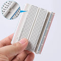 400 Tie Points Half Size Solderless Breadboard Solder Less Breadboard Prototyping Board - a white plastic prototyping board held in a hand with a circular inset magnifying the pin labels.