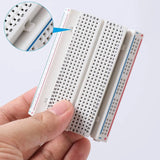 400 Tie Points Half Size Solderless Breadboard Solder Less Breadboard Prototyping Board - a white plastic prototyping board held in a hand with a circular inset magnifying the pin labels.
