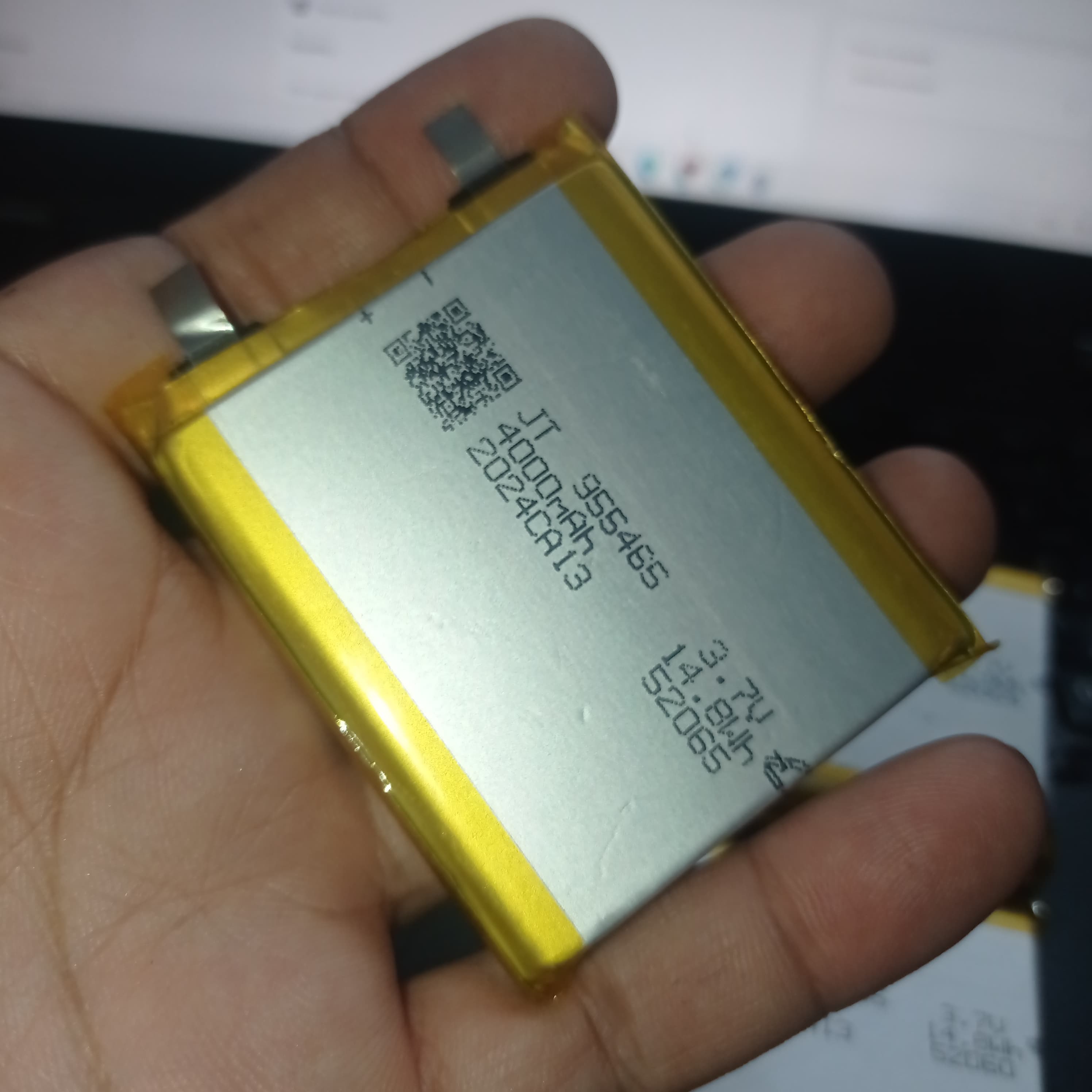 4000mAh 3.7V Lithium Ion Battery Price 9.5mm X 54mm X 65mm - a rectangular silver cell with yellow tape edges and two metal contact tabs, held in a hand.