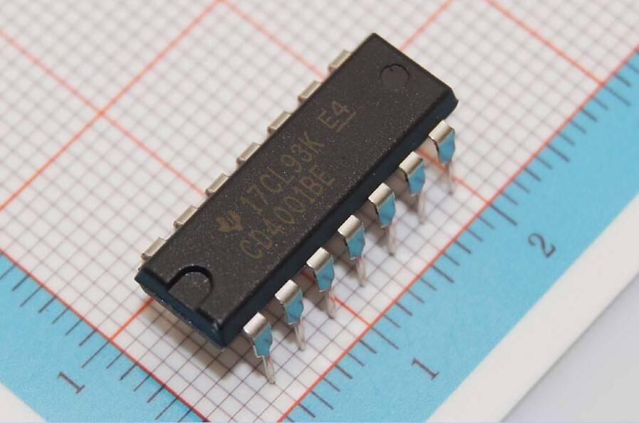 4001 Quad 2 Input Nor Gate IC - a black 14-pin dual in-line package integrated circuit resting on a grid-patterned surface.