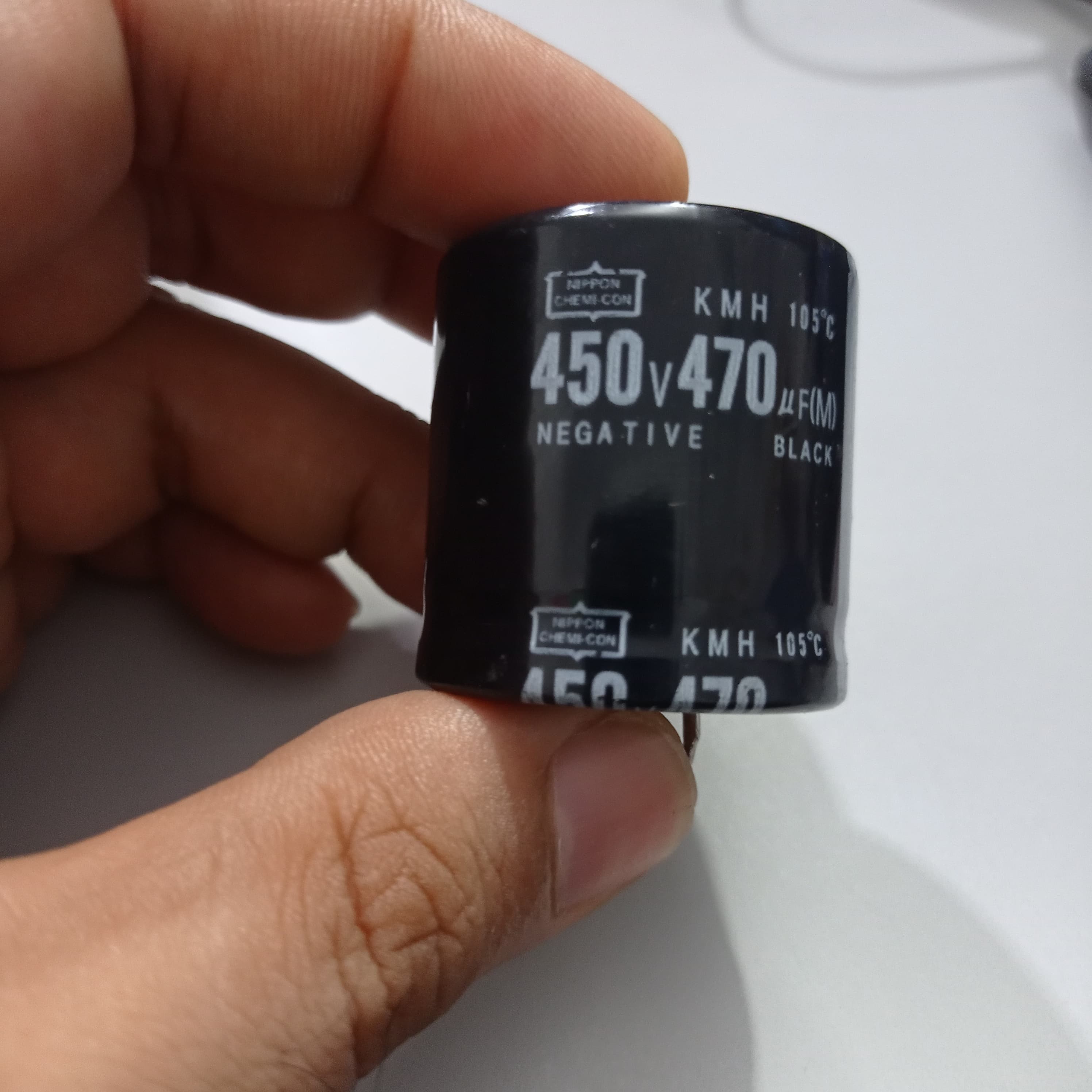 470uF 450V Capacitor - a black cylindrical electrolytic capacitor held by fingers, showing printed specifications including 450V, 470µF, and 105°C.