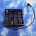 4xaa Battery Holder In Lahore Pakistan - a black plastic four-slot battery case with metal springs and a two-pin connector attached by a black wire.