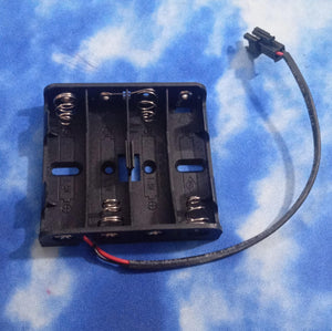 4xaa Battery Holder In Lahore Pakistan - a black plastic four-slot battery case with metal springs and a two-pin connector attached by a black wire.