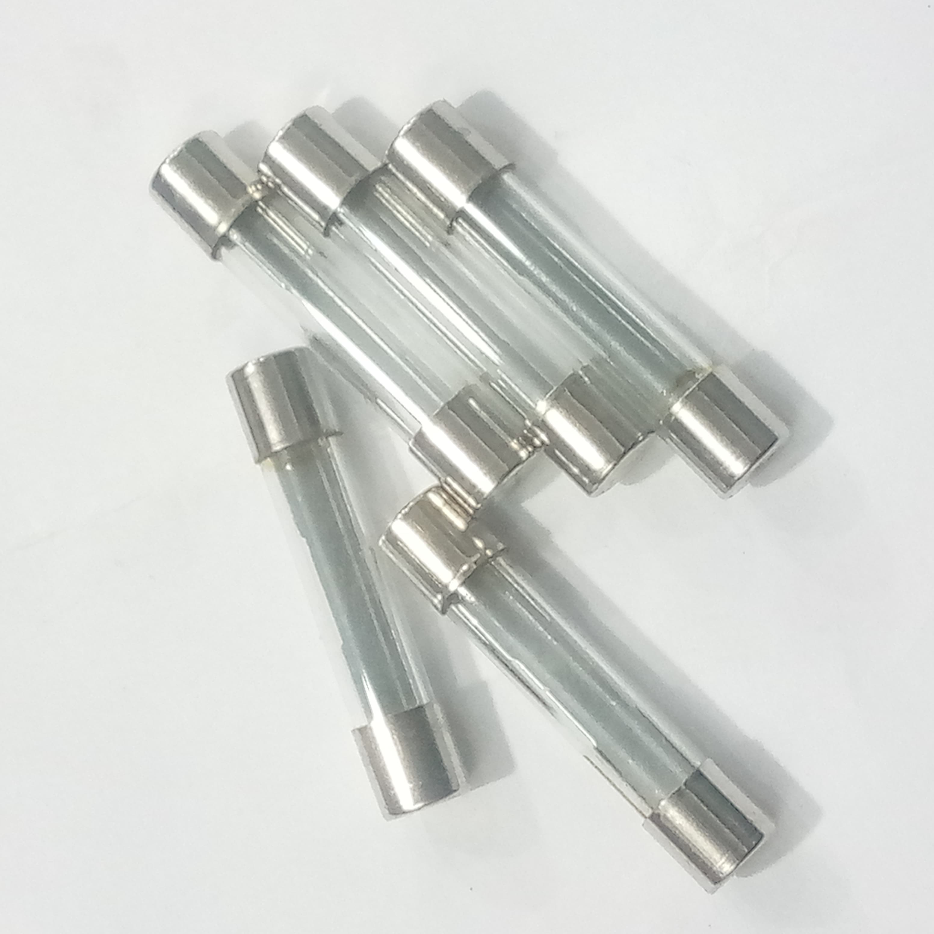 5 Pcs 6MMX21MM 35A Fuse - top-down view of five clear glass cylindrical fuses with silver metal end caps arranged in a small pile on a white surface.