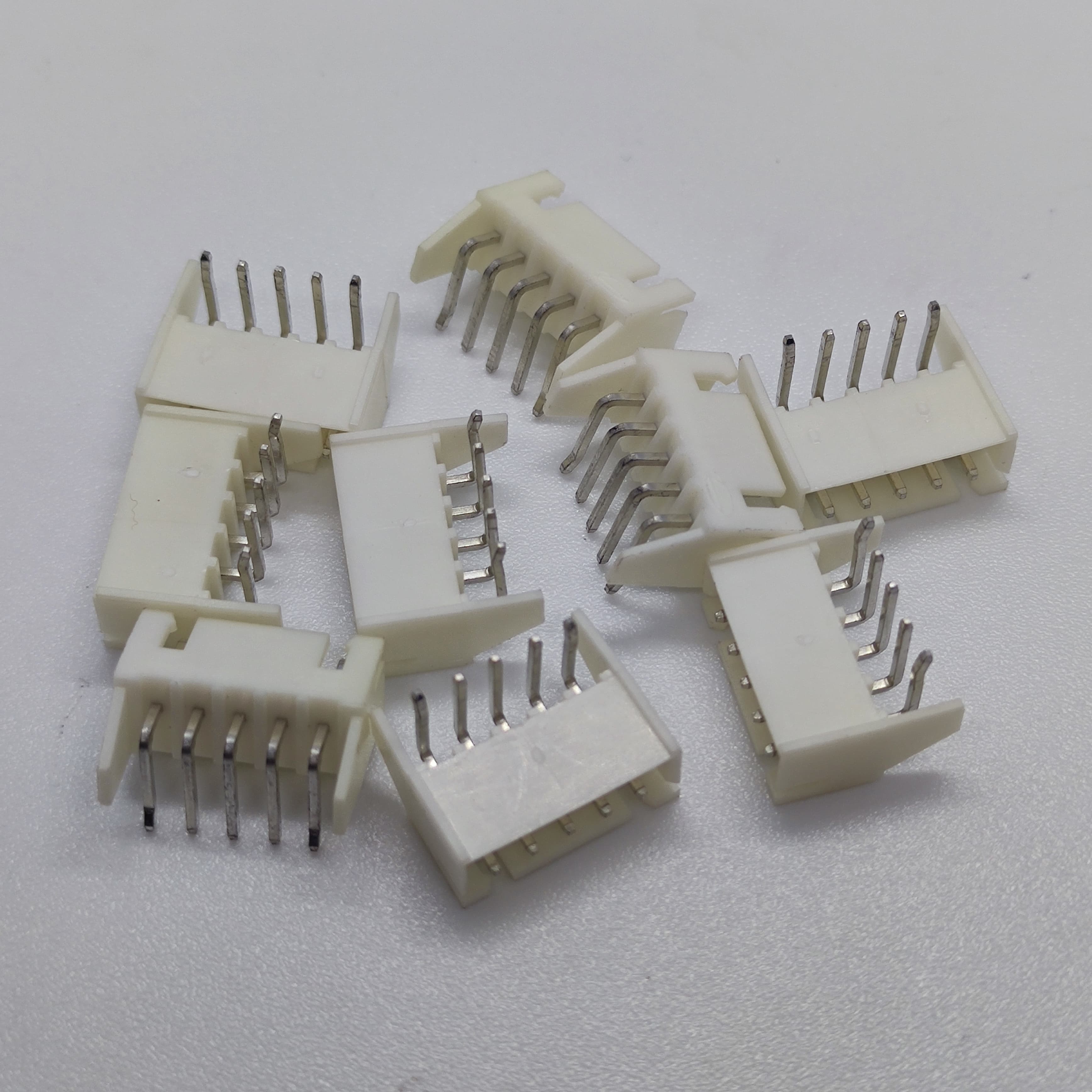5 Pin Right Angle Male 2.5mm JST Xh Style PCB Mount Connector - a pile of several white plastic connectors with five metallic pins each.