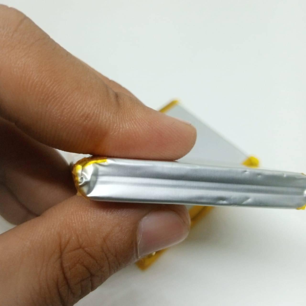 5000mAh 3.7V Lithium Ion Battery Price - a close-up shot of a hand holding the thin, silver, rectangular pouch-style battery with yellow taped edges.