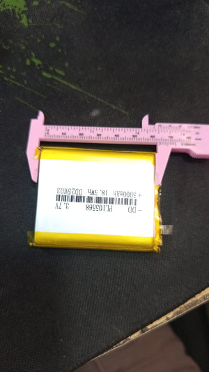 5000mAh 3.7V Lithium Ion Battery Price - a rectangular yellow cell being measured for width with a pink plastic vernier caliper.