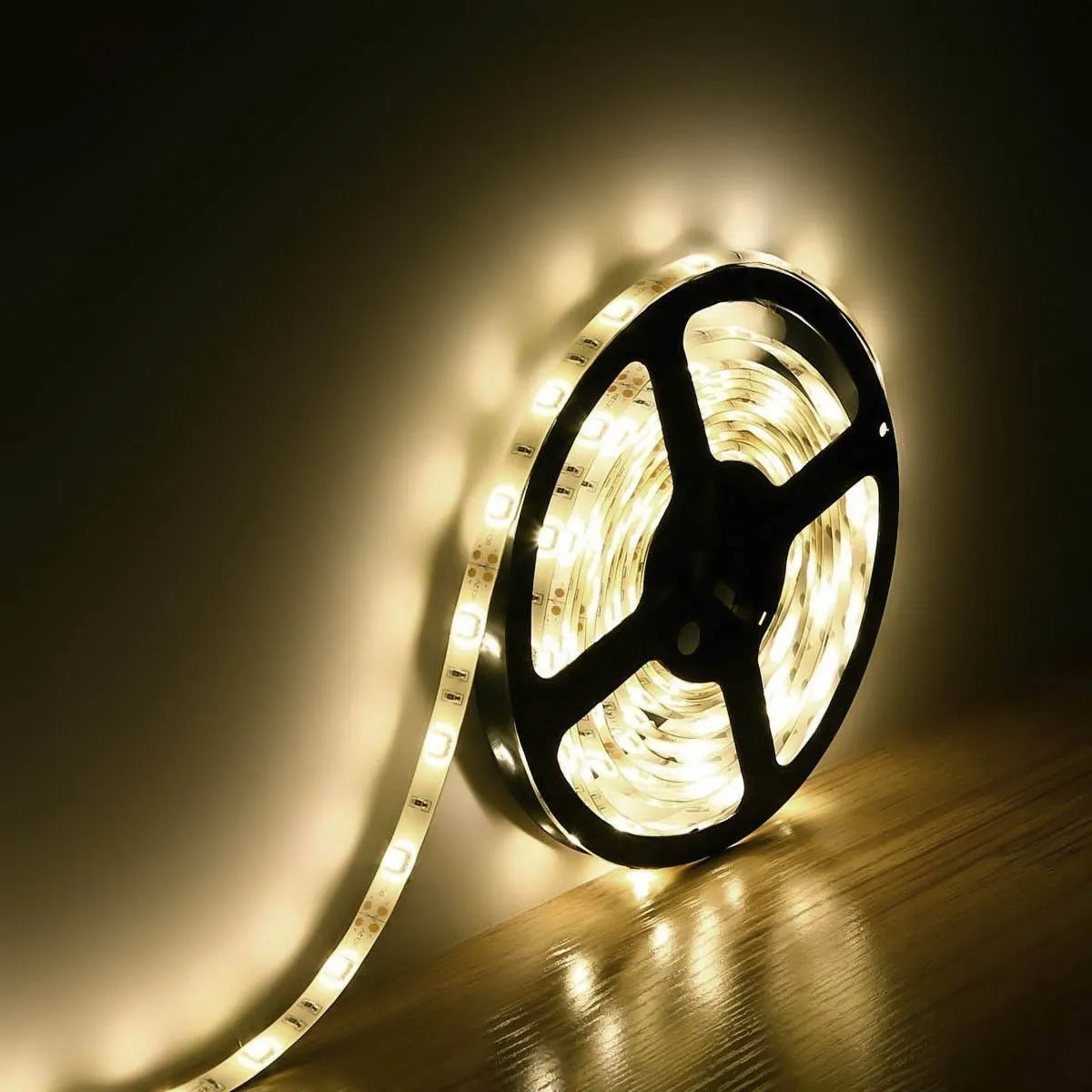 5m 5050 SMD 300 LED Warm White Waterproof Strip Lighting 12V Flexible - coiled on a black plastic spool and illuminated against a wall.