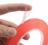 5mm 5 Meter Transparent Adhesive Double Sided Tape For Mobile LCD & Touch Screen - a hand holding a roll of red-backed adhesive tape with a partially peeled clear liner.