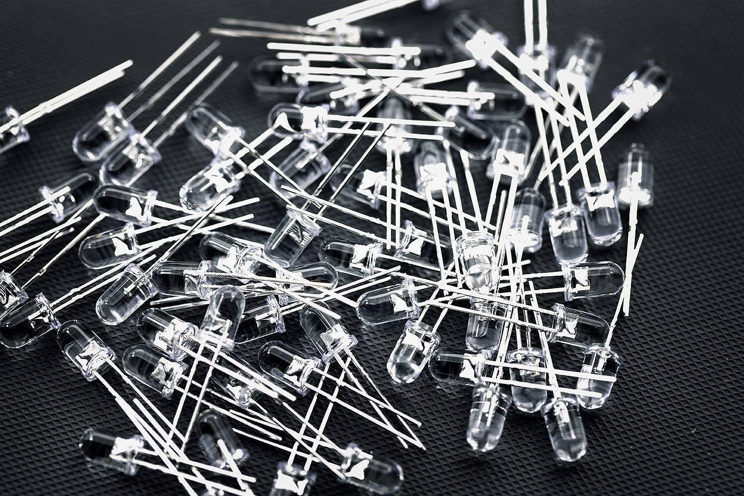 5mm Blue LED - shown as a large pile of individual, clear-cased light-emitting diodes with two metal wire leads each, scattered on a dark surface.