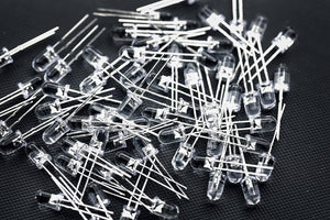 5mm Blue LED - shown as a large pile of individual, clear-cased light-emitting diodes with two metal wire leads each, scattered on a dark surface.