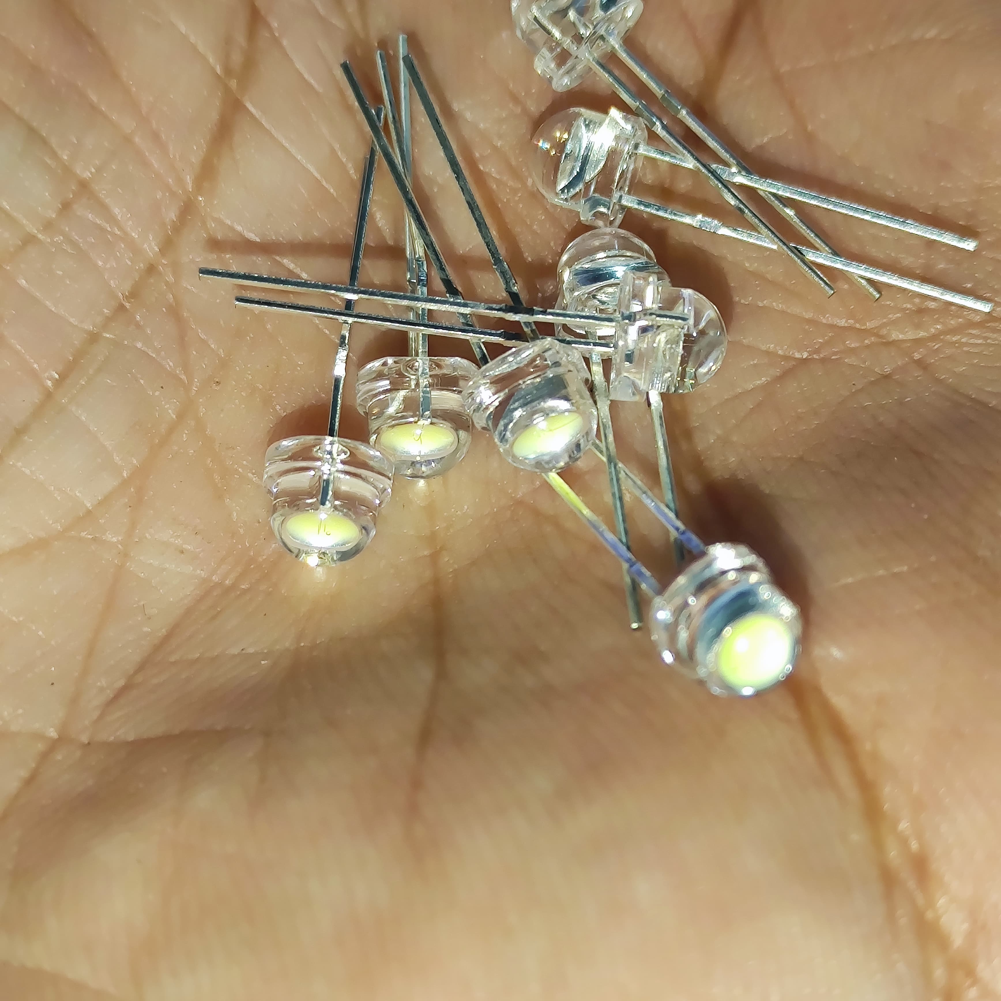 5mm F5 Straw Hat LED White - High Power, Ultra Bright Indicator Light For DIY Projects (0.5W, 3-3.2V) - a close-up shot showing multiple clear, dome-shaped LEDs with metal pins held in a person's palm.