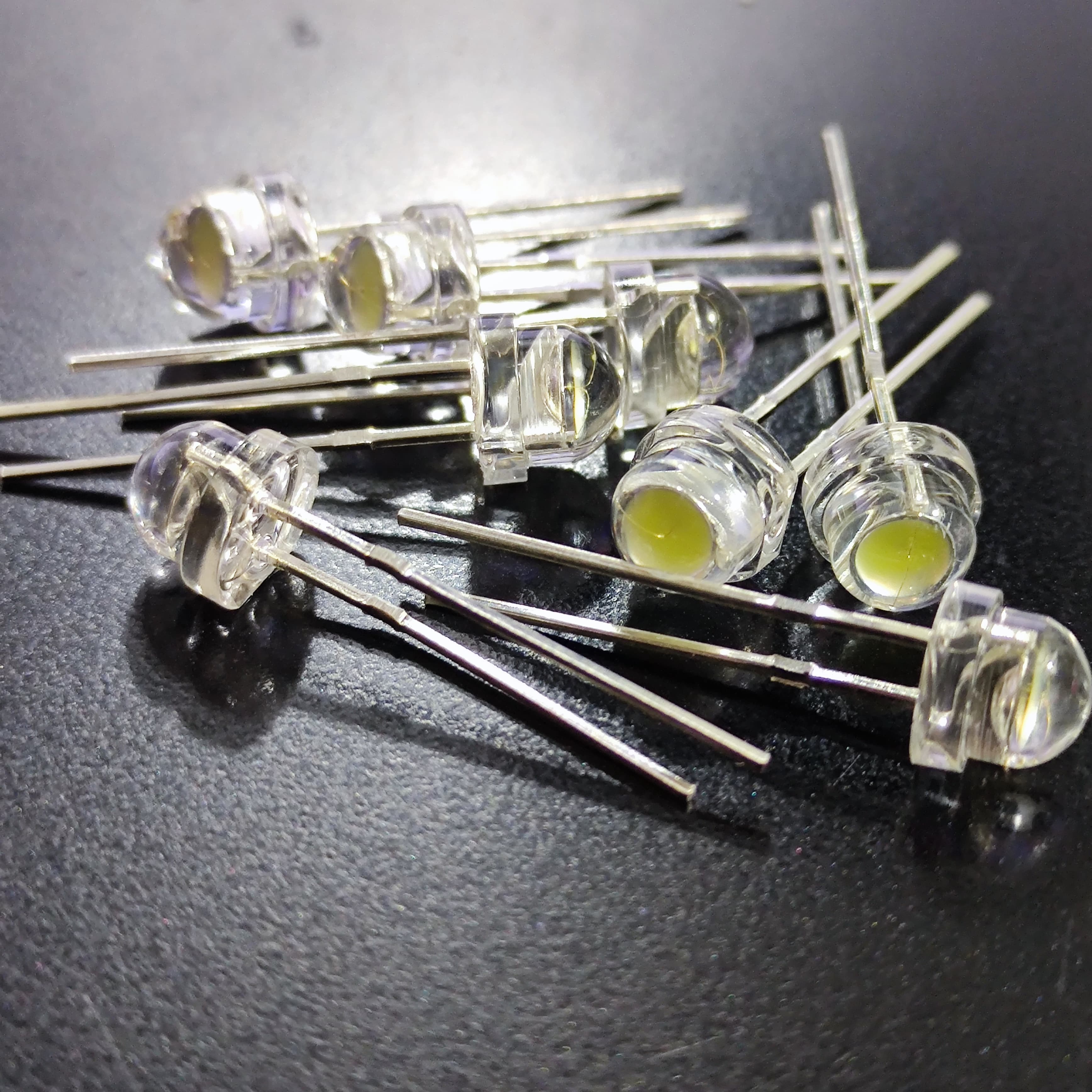 5mm F5 Straw Hat LED White - High Power, Ultra Bright Indicator Light For DIY Projects (0.5W, 3-3.2V) - a pile of small, clear, dome-shaped light-emitting diodes with two metal pins each, arranged on a dark surface.
