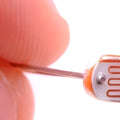 5mm Light Dependent Resistor LDR Sensor - a close-up showing the circular component with a serpentine copper-coloured track held between two fingers.