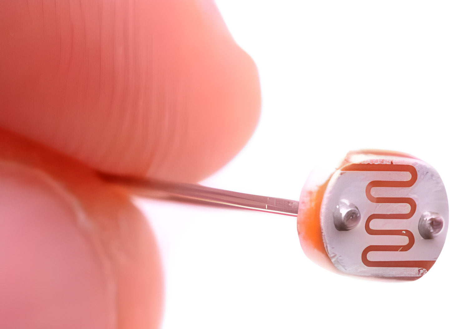 5mm Light Dependent Resistor LDR Sensor - a close-up showing the circular component with a serpentine copper-coloured track held between two fingers.