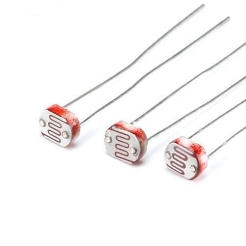 5mm Light Dependent Resistor LDR Sensor - a close-up view of three small, circular electronic components with red, wavy, light-sensitive patterns.