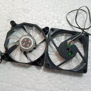 5V Fan With LED - two black square cooling fans with translucent blades and attached wires, viewed from the front and back.