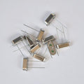 6.144M 6.144MHz Crystal Oscillator For Solar Inverter - a pile of silver, rectangular, two-pin metal components on a white background.
