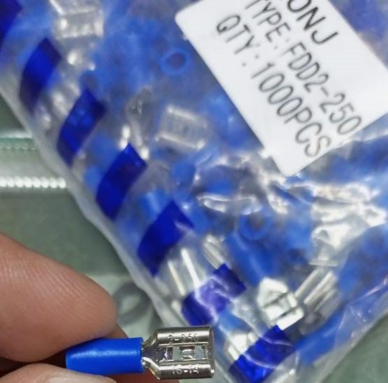 6.3mm Crimp Terminal Female Pre Insulated Electrical Connectors - a single blue connector held in hand with a bulk bag labeled FDD2-250 behind it.
