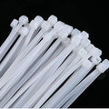 6 Inch 100mm PVC Cable Tie - a bundle of white plastic cable ties with locking heads arranged against a black background.