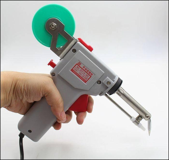60W Manual Automatic Tin Welding Gun 941-60 Soldering Gun - a grey handheld soldering gun with a green solder wire spool mounted on top, held in a person's hand.