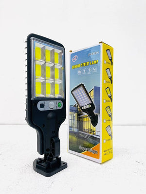616-4 Motion Sensor Street Lamp - shown with its black plastic body, LED light panel, power button, sensor, mounting bracket, and its yellow packaging box.
